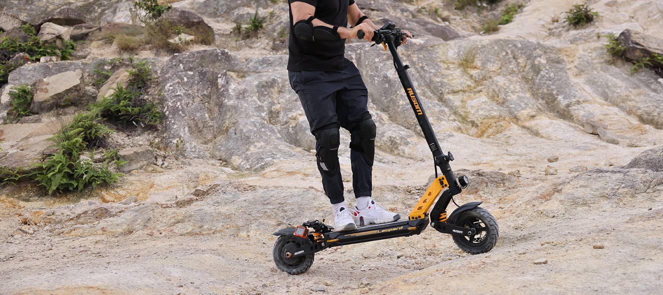 Ausom Leopard off-road electric scooter on rocky terrain with rider wearing protective gear